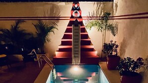A swimming pool with a red and white decorative structure at the end, surrounded by potted plants. - 2 bed, 2 bath house w/ private pool, pyramid waterfall, short walk to beach. (Barra de Navidad)