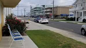A hotel with a covered outdoor seating area, a stop sign, and a parking lot with several cars.