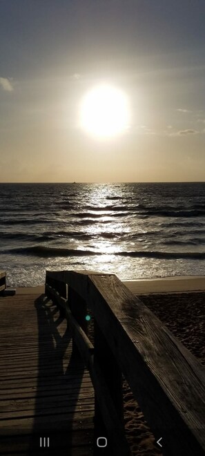 A wooden pier extending into calm waters with the sun low on the horizon. - 1 block from the beach . Ocean view cozy beach house . Backyard with fire pit .  (Wildwood Crest)