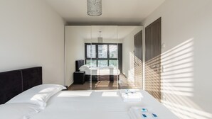 Habitación de hotel moderna con una cama grande, un escritorio y vistas al exterior a través de la ventana.