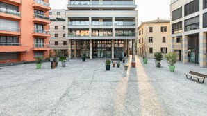 Un edificio de varios pisos con un patio central, plantas en macetas y una banca.