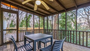 A covered outdoor deck with a table and chairs, a ceiling fan, and a view of trees. - 6807 Jones Valley · ֍The Strata֎ 4000 SQ Feet, 6 BR, Pool Table (Huntsville)