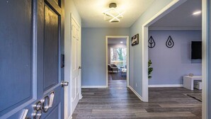 A hallway with a wooden floor, a door with a number, and a ceiling light fixture. - 6807 Jones Valley · ֍The Strata֎ 4000 SQ Feet, 6 BR, Pool Table (Huntsville)