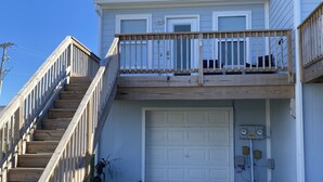 A two-story house with a wooden staircase leading to a balcony, a garage, and a driveway. - 2 blocks to the beach- Pool- King-sized beds- Sound- SUPs- Linens- Beachgear (North Topsail Beach)