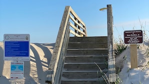 A wooden staircase leading to a sandy beach area with informational signs. - 2 blocks to the beach- Pool- King-sized beds- Sound- SUPs- Linens- Beachgear (North Topsail Beach)