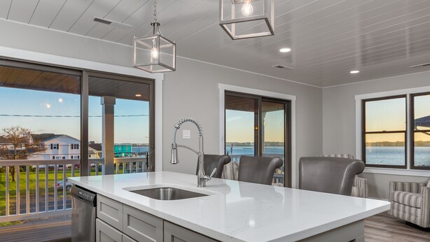 A modern kitchen with a large island, stainless steel appliances, and a view of the water.