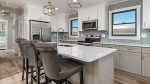 A modern kitchen with a central island, stainless steel appliances, and pendant lighting.