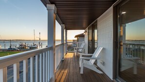 A wooden deck with white railings, overlooking a marina with boats.