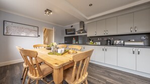 A modern kitchen with white cabinets, a wooden dining table, and a large map on the wall. - Heacham Hidey Hole, Heacham, Norfolk (Heacham)
