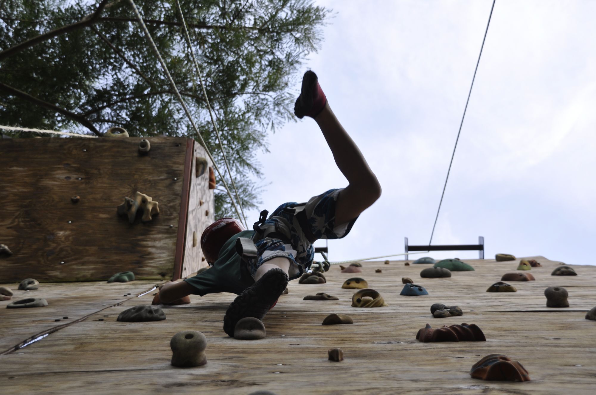 Una persona escalando una pared de madera con diferentes agarres.
