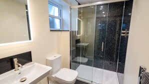 Une salle de bain moderne avec une douche à parois de verre, des toilettes blanches et un lavabo avec un miroir au-dessus.