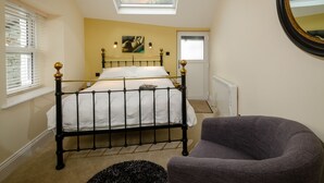 A bedroom with a bed, a chair, a skylight, a painting, and a window. - Anns Cottage, Chapel Stile (Ambleside)