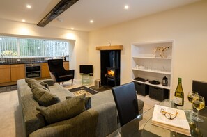 Una sala moderna con sofá, chimenea, zona de cocina y mesa de comedor con vasos y una botella.