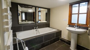 Ein modernes Badezimmer mit einer Badewanne, einem Waschbecken und einem großen Spiegel.