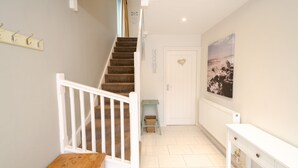 A staircase with white railings leading to a door marked "HOME" with a heart decoration. A small table and basket are placed near the door.