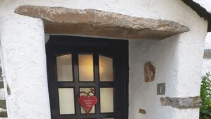 Una puerta negra con un panel de vidrio esmerilado y un letrero con forma de corazón que dice 'Welcome to Valentine Cottage'.