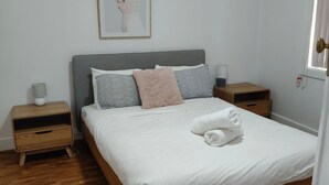Un letto rifatto con copriletto bianco, due comodini con lampade e un quadro appeso alla parete.