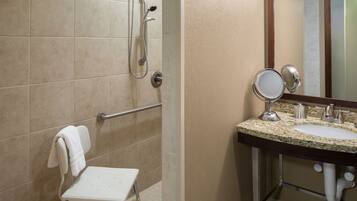A bathroom with a shower, a sink with a mirror, and a small step stool.