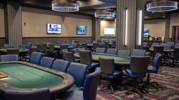 A casino room with multiple blackjack tables, chairs, and overhead lighting.