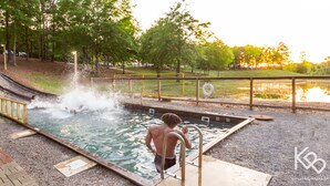 A swimming pool with a slide, surrounded by trees and a grassy area. - studio rm w/ full kitchen, 1 bth , private deck, & WiFi @ Kick Back Ranch. (Ramer)