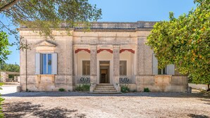 A historic building with a symmetrical facade, a central entrance with steps, and a gravel driveway. - Masseria Pugliese Deluxe (Ostuni)