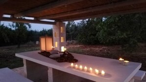 An outdoor dining area with a long table and benches, surrounded by candles and a lantern. - Masseria Pugliese Deluxe (Ostuni)