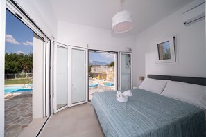 Ein Schlafzimmer mit Bett, Blick auf einen Pool und einem Balkon.