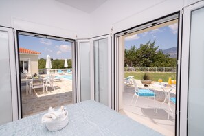 Ein Schlafzimmer mit Blick auf einen Außenpool und Terrassenmöbel.