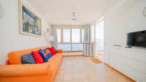 A bright living room with a sofa, a television, and a large window offering a view of the sea. - La Gemma di Praiano (Praiano)