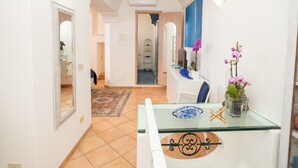 A narrow hallway with a glass table, a potted orchid, and a blue chair. - La Gemma di Praiano (Praiano)