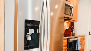 A stainless steel refrigerator with a built-in ice maker and a microwave above it.