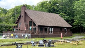 A lodge with a large deck, outdoor seating, and a fire pit.