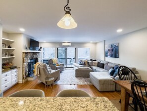 Una sala de estar moderna con chimenea, comedor y cocina.