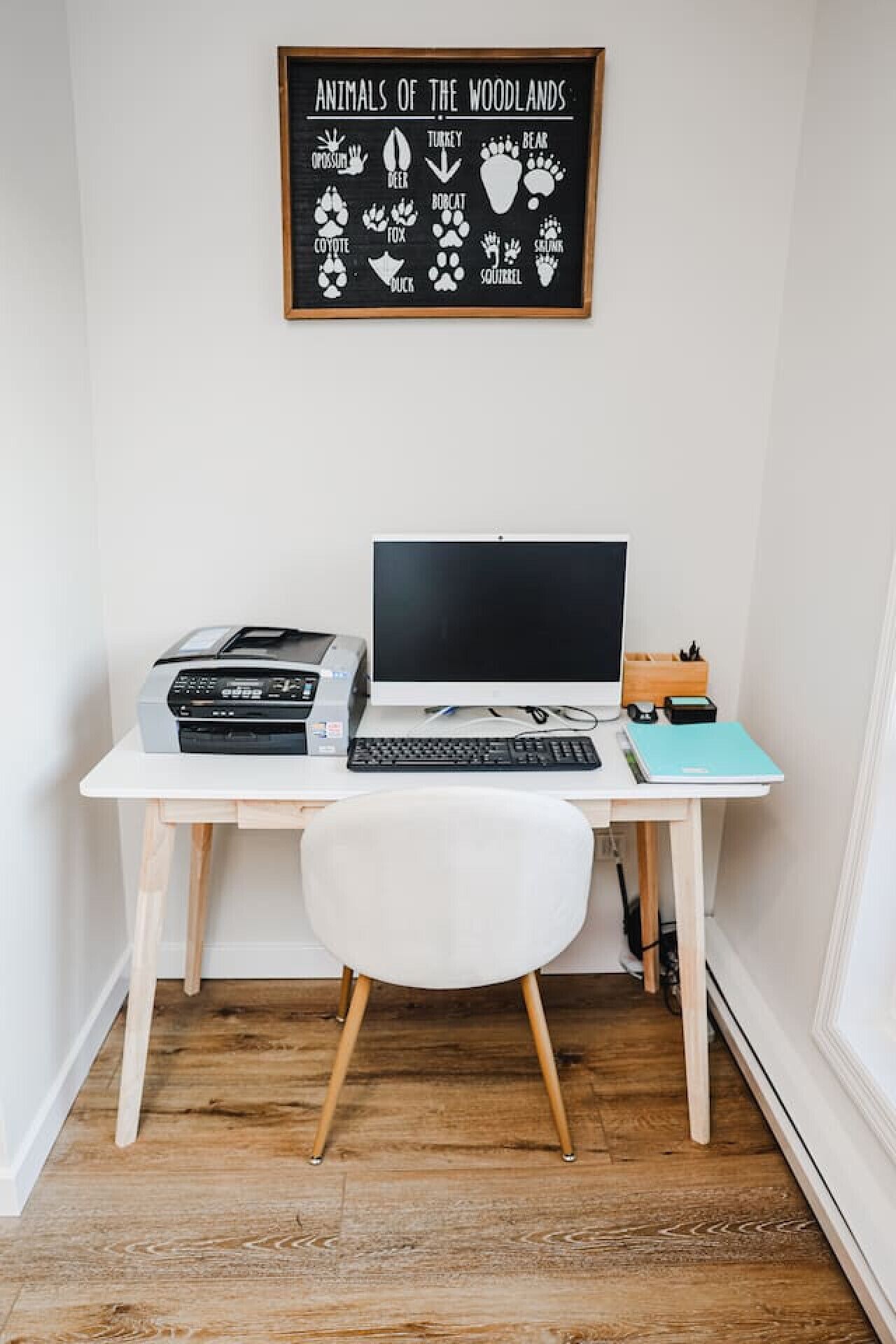 Un espace de travail comprenant un bureau, un ordinateur portable, une imprimante et une chaise.