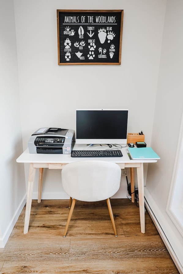 Un espacio de trabajo con un escritorio, una laptop, una impresora y una silla.
