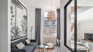 A modern living room with a grey sofa, a round coffee table, and a large framed artwork on the wall.