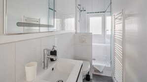 A modern bathroom with a white sink, mirror, and shower.