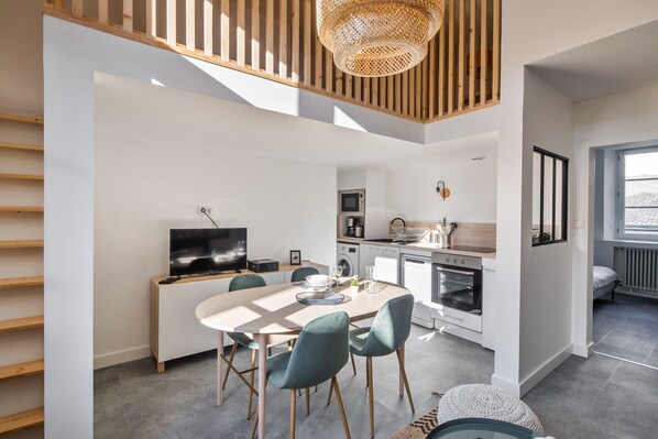Una cocina moderna con comedor, listones de madera en el techo y un ventanal grande.