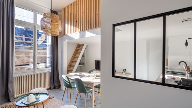 A modern interior with a dining area, a staircase, and a large window.
