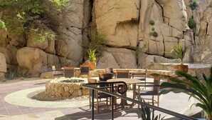 An outdoor patio area with stone flooring, wooden furniture, and potted plants. - Private Oceanfront Luxury (Cabo San Lucas)