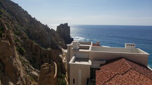 A coastal building with a view of the sea and rocky cliffs. - Private Oceanfront Luxury (Cabo San Lucas)