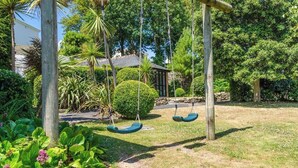 A garden with a wooden swing set and a stone pathway. - Charming Summerhouse in Fowey Town Center (Cornwall)