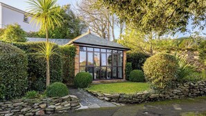 A small, modern house with a glass front and a stone pathway leading to the entrance. - Charming Summerhouse in Fowey Town Center (Cornwall)