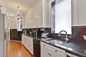 A modern kitchen with white cabinetry, a stainless steel sink, and a dishwasher.