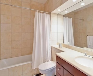 A bathroom with a bathtub, toilet, sink, and a mirror.