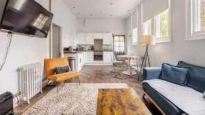 A modern living room with a sofa, a coffee table, and a TV mounted on the wall. - Charming Schoolhouse Apartment by Fowey Harbour (Cornwall)