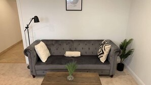 A living room with a grey sofa, a wooden coffee table, a framed picture on the wall, and a floor lamp. - Studio flat in the heart of Chicago's Gold Coast (Chicago)