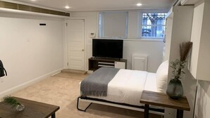 A bedroom with a bed, a TV, a window, a door, and a small table. - Studio flat in the heart of Chicago's Gold Coast (Chicago)
