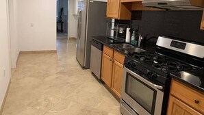 A kitchen with wooden cabinets, a stainless steel refrigerator, a stove, and a dishwasher. - Studio flat in the heart of Chicago's Gold Coast (Chicago)
