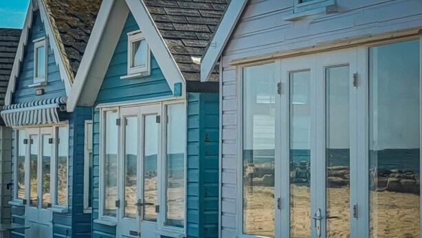 Una hilera de casas de campo frente al mar, con ventanas amplias y techo de piedra.